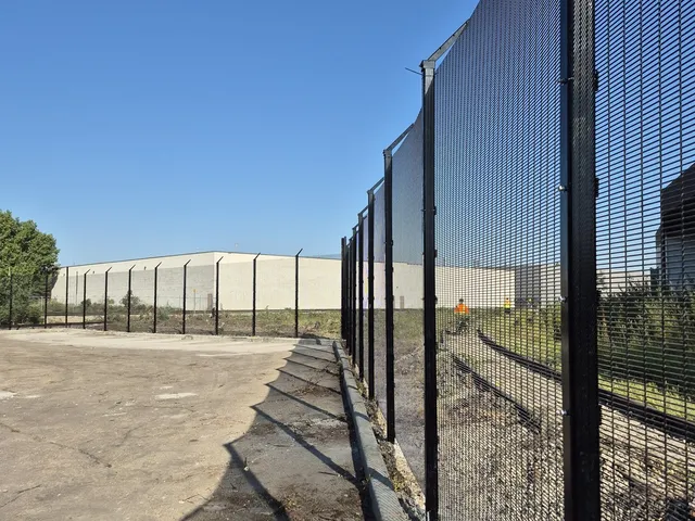 Black welded mesh security fence with barbed wire, Canplas Industries