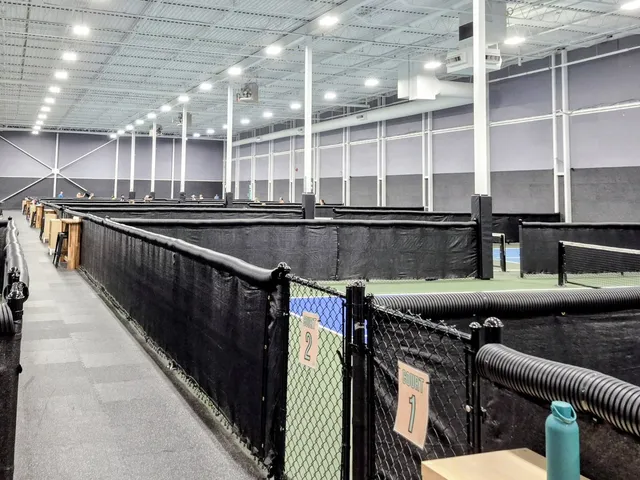 Indoor pickleball courts with black chain link and windscreen, Edmonton Pickleball Center
