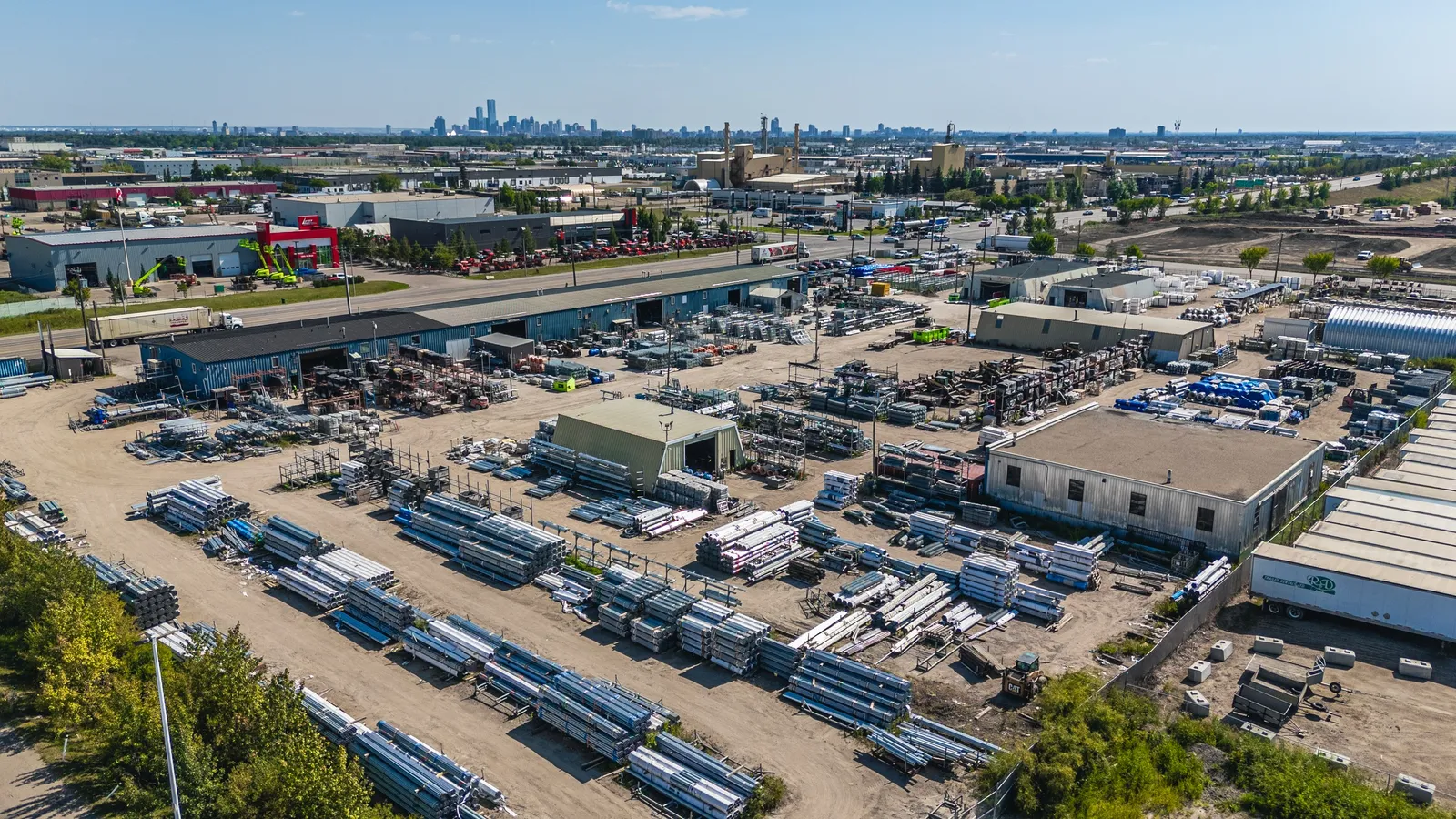 Pipe and tube inventory across the Phoenix Fence Edmonton yard with the city skyline beyond