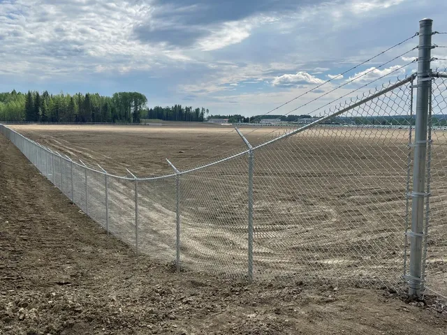 Galvanized chain link with barbed wire on a rural site