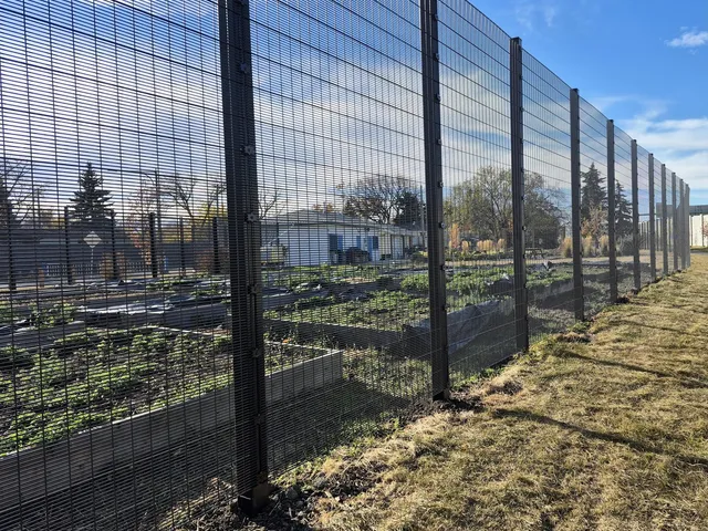 Black welded wire fence around the community garden, Elmwood Community Hall