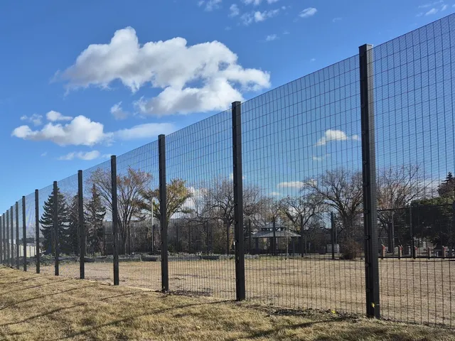 Black welded wire fence along the field, Elmwood Community Hall