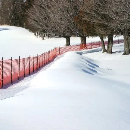 Orange snow fence along a winter roadway