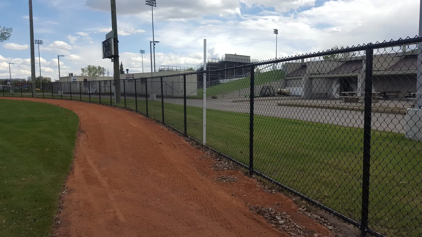 Black chain link fence following the warning track of a ball diamond