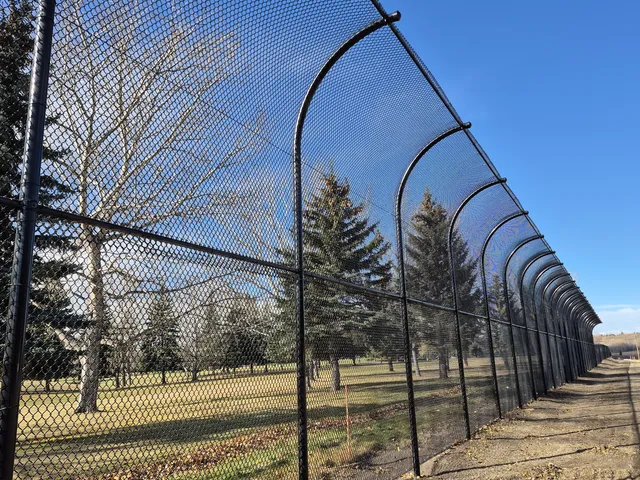 Golf course fence with curved overhang