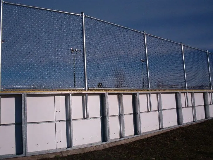 Chain link fence mounted above the boards of an outdoor hockey rink