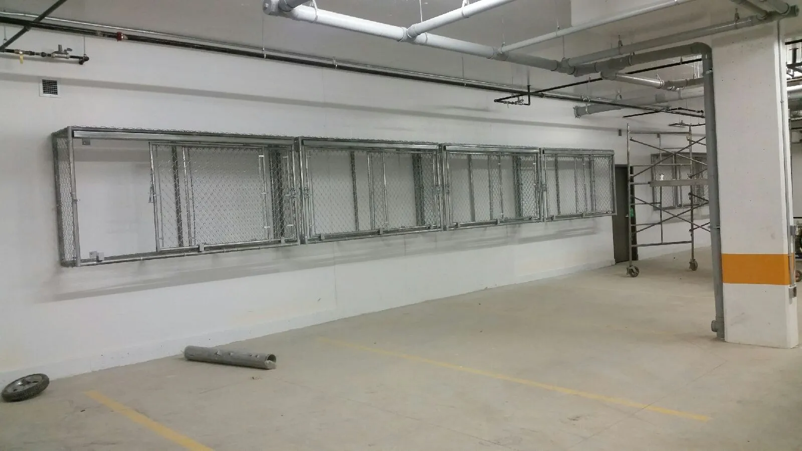 Wall mounted chain link storage cages above parking stalls in an underground parkade