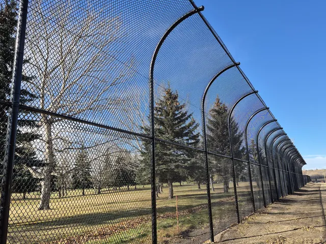 Black chain link golf course fence with curved overhang, Sturgeon Golf Course